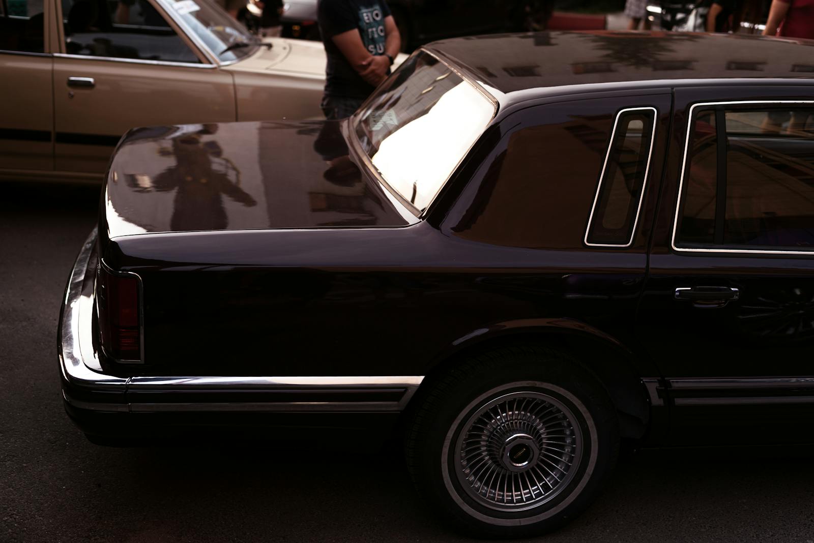 Vintage black Lincoln parked at an outdoor car show, reflecting luxury and style.