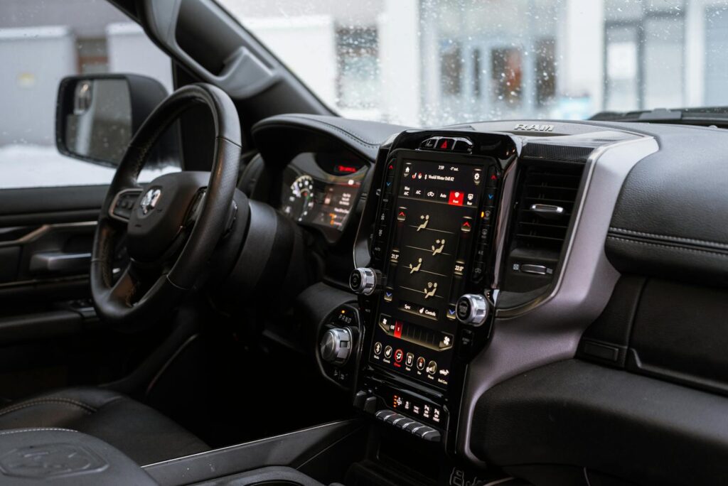 Interior view of a modern vehicle featuring a digital touchscreen dashboard and steering wheel.