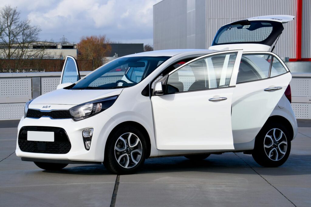 White compact car with open doors captured in an urban setting, ideal for vehicle promotion.