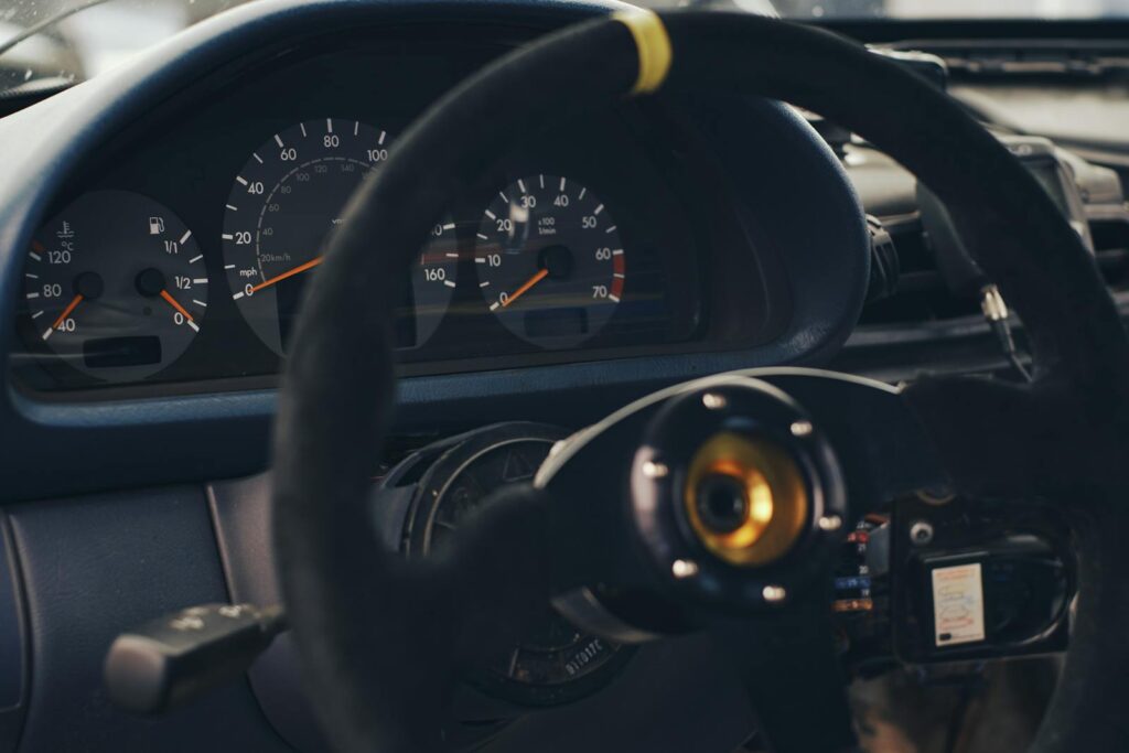 Detailed shot of a car's dashboard featuring a steering wheel and speedometer gauges.