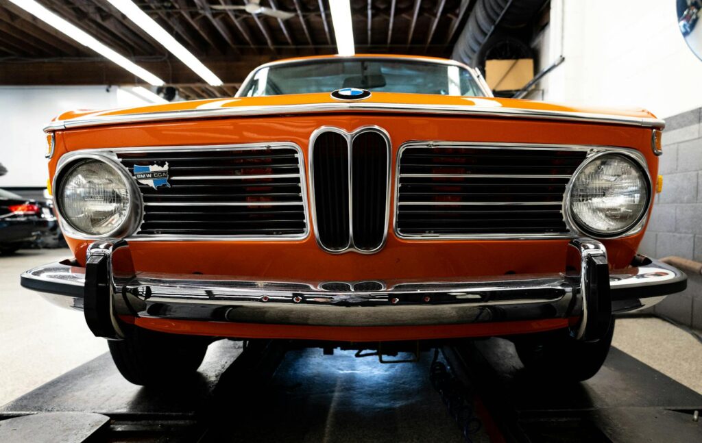 Front view of an orange vintage BMW car indoors, showcasing its classic design.