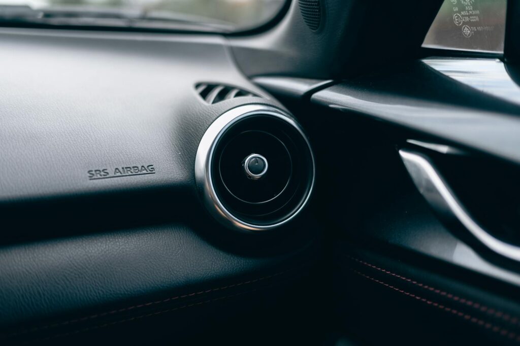 Close-up of a car interior featuring an air vent and SRS airbag text on the dashboard.