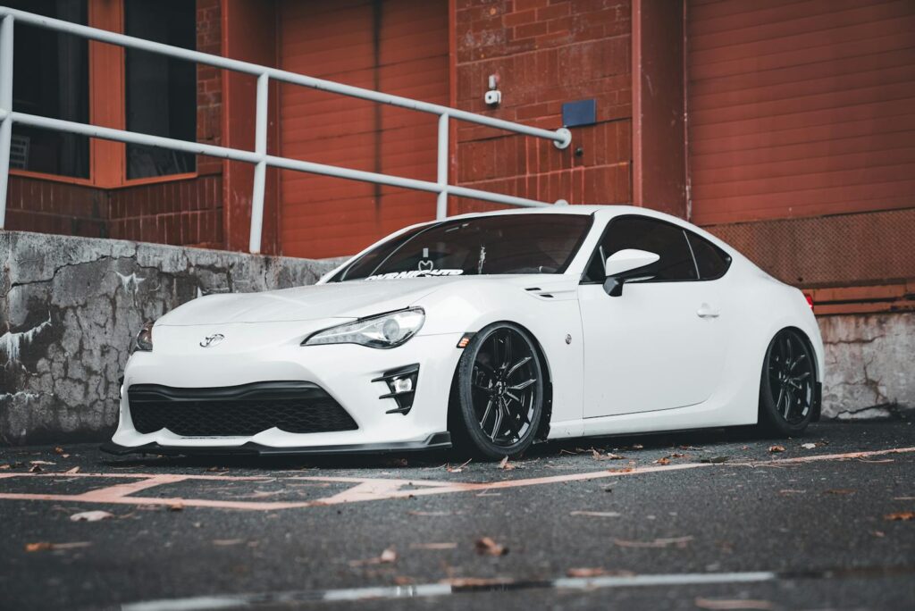 A sleek white sports car parked outdoors near a brick building.