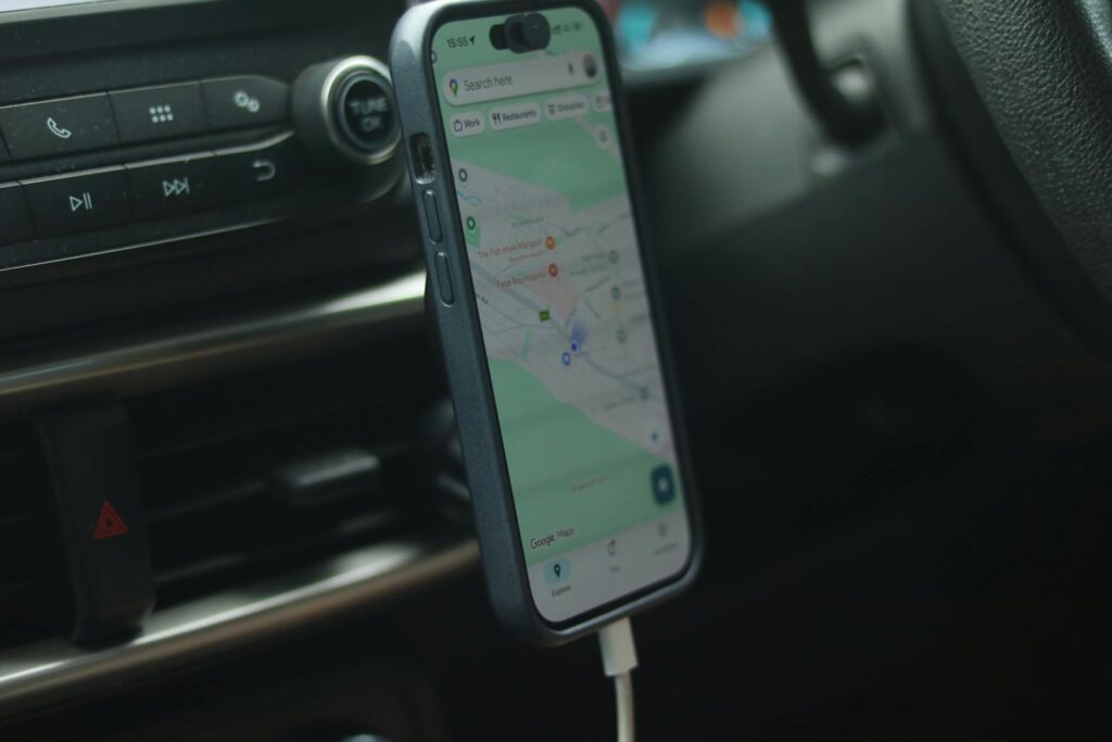 A smartphone with a map app displayed inside a car, showing modern navigation.