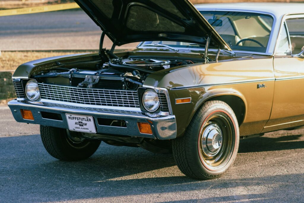 An old car with a hood open on the street