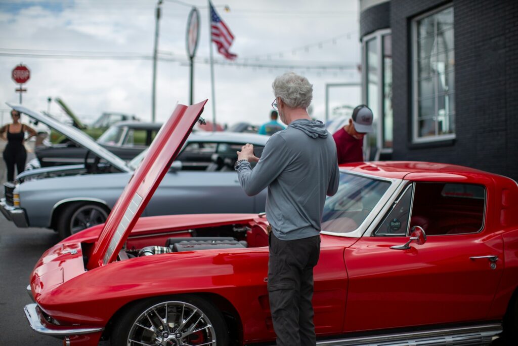 A man standing in front of a red car
