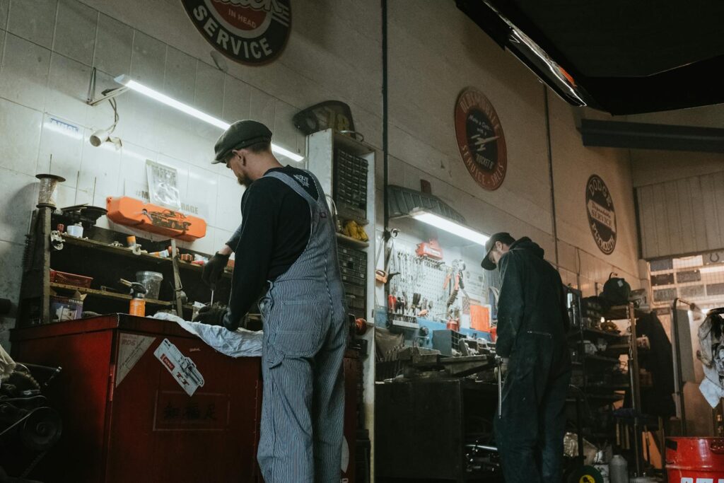 Two mechanics in a garage working on vehicle repair and maintenance.