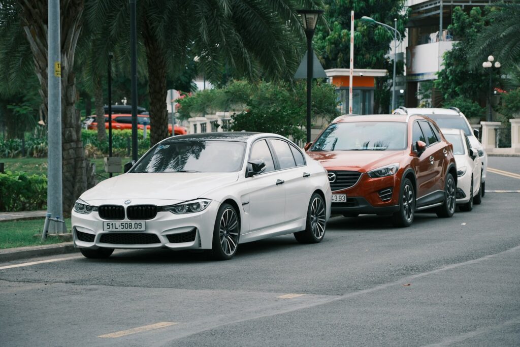 Cars are parked on the street, next to each other.