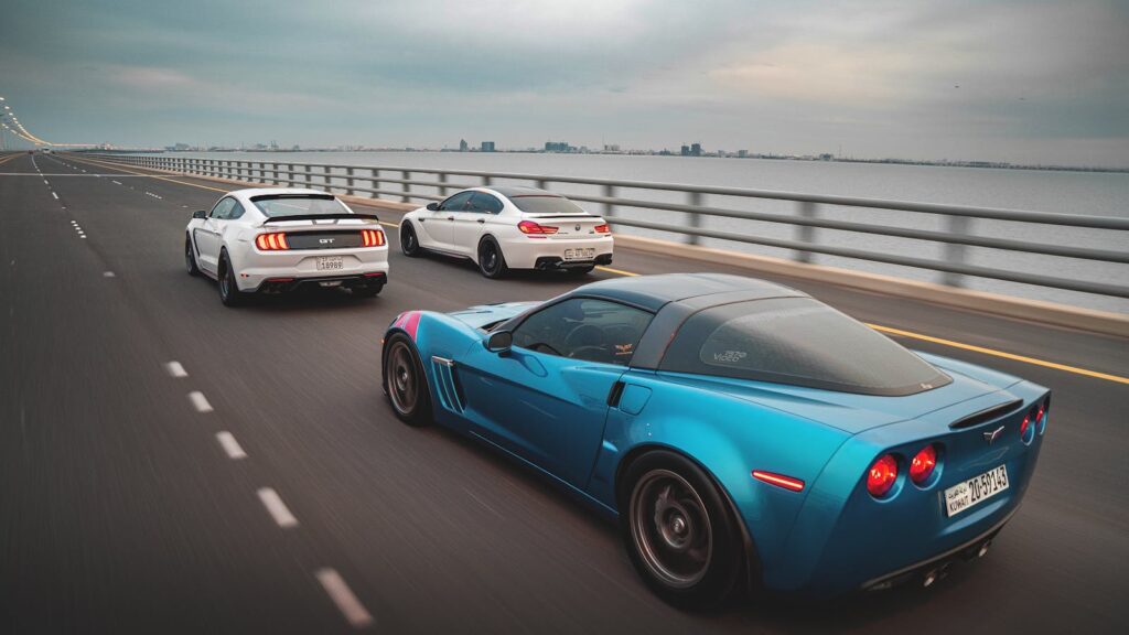 Fast-moving sports cars racing over a vast ocean bridge, showcasing speed and precision.