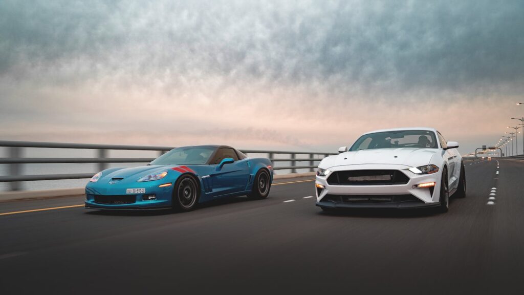 Dynamic capture of two sports cars racing on a highway under a dramatic sky, emphasizing speed and motion.