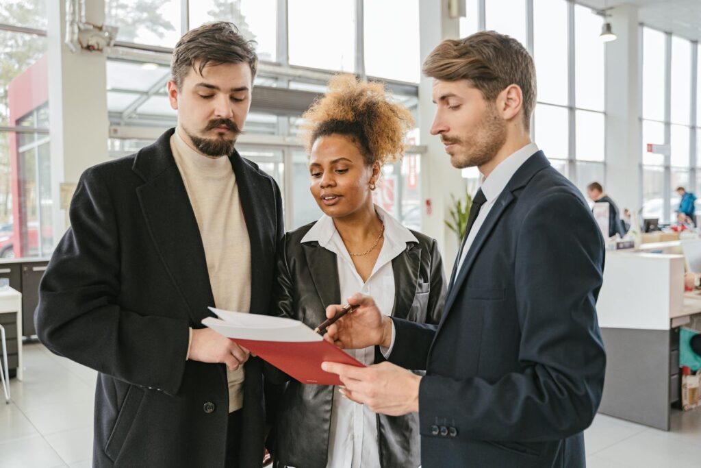 Three professionals discussing and reviewing documents in a modern office space.
