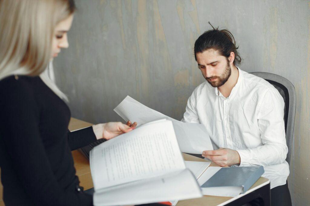 Two professionals reviewing important documents in a modern office setting.