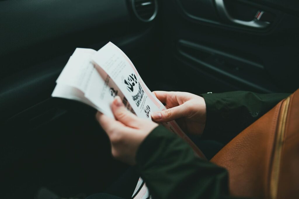 Close-up of hands holding a brochure inside a car, creating an intimate and focused scene.