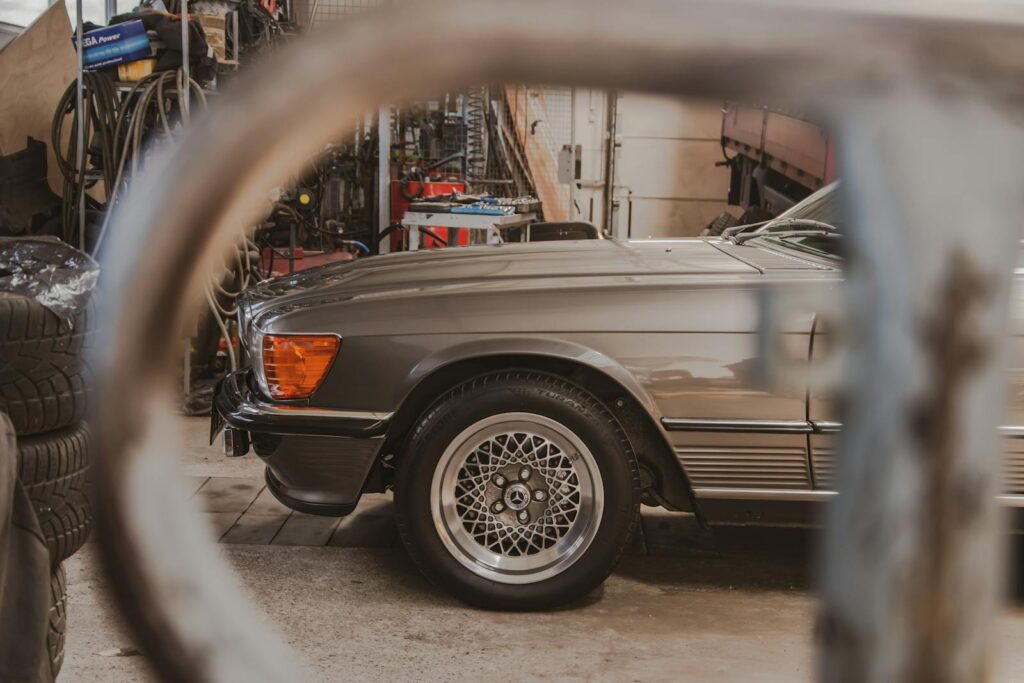 A vintage Mercedes-Benz parked in a rustic garage, showcasing its elegant wheel design.