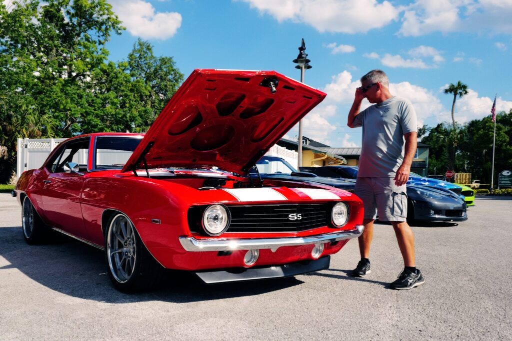 a man standing next to a red and white car
