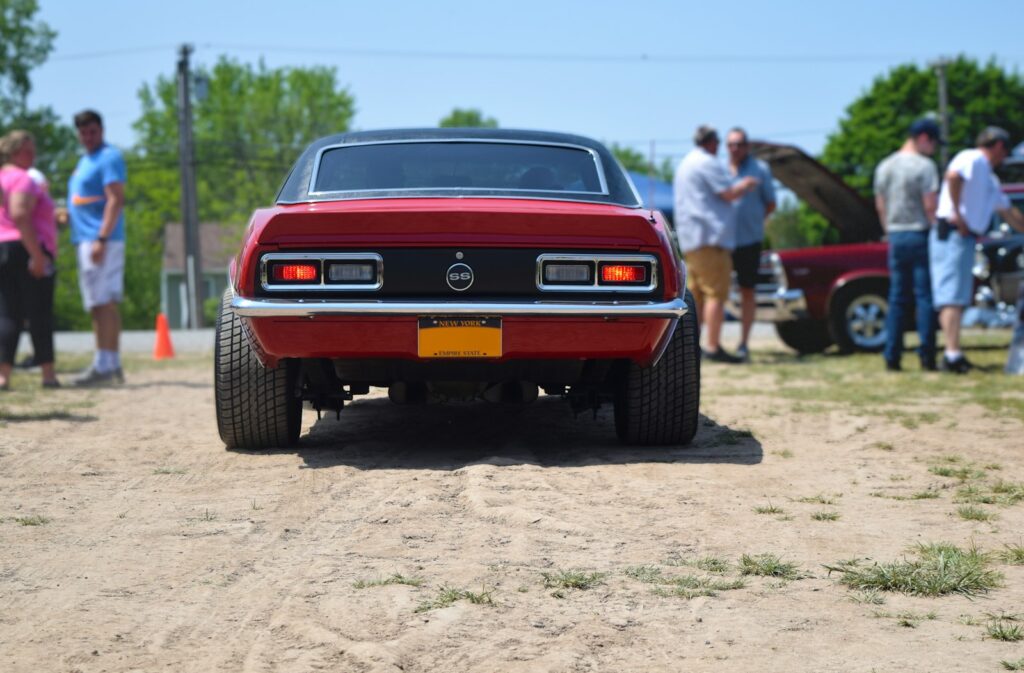 a red car parked on top of a dirt road