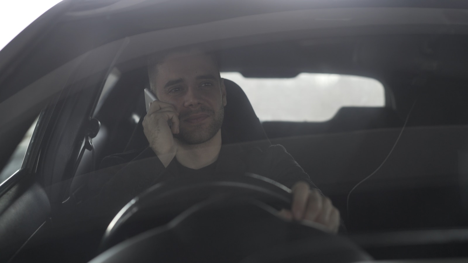 Man talking on phone while driving a car.
