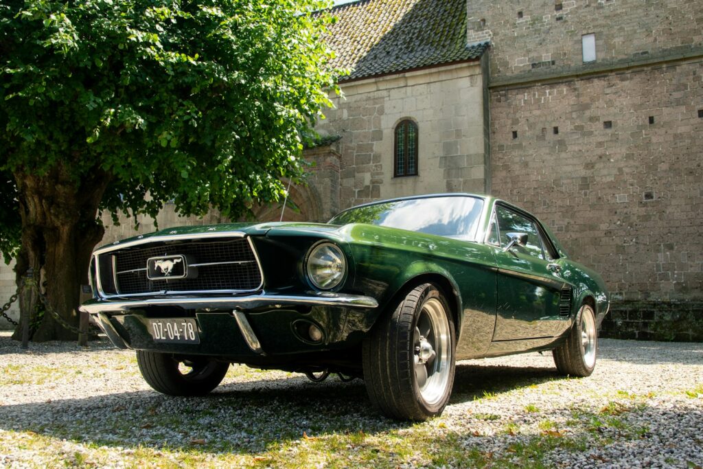A green mustang parked in front of a brick building