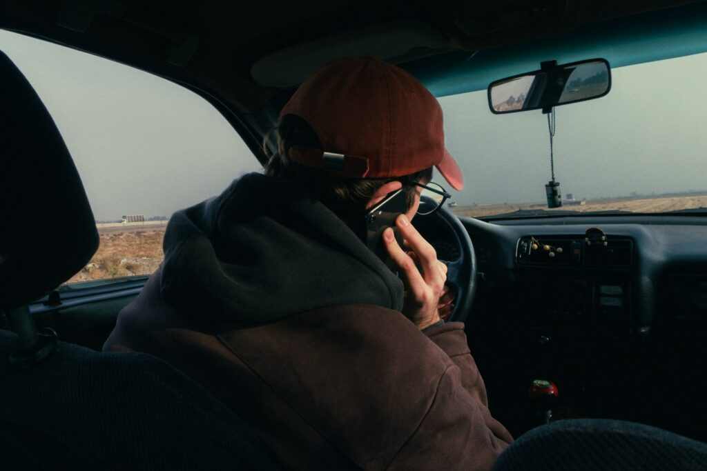 Person in car wearing a hat and glasses.