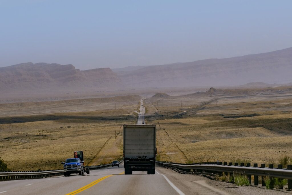 a semi truck driving down a highway in the desert