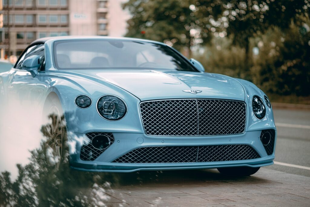 A blue bentley is parked on the side of the road.