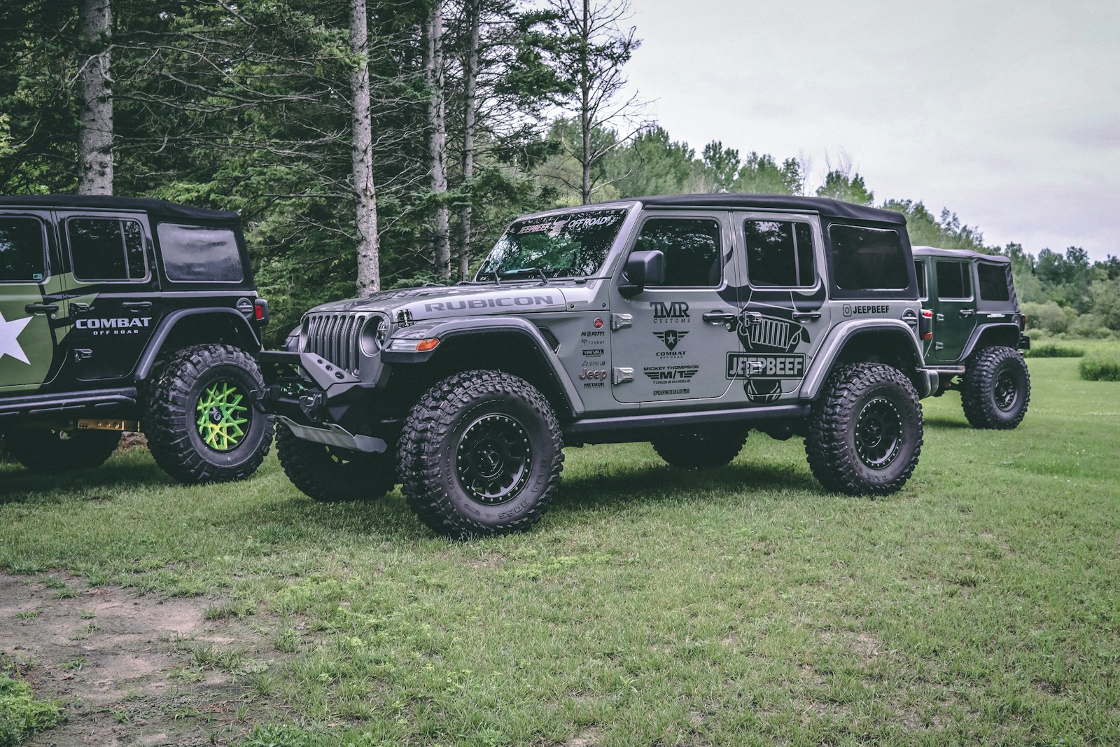 two jeeps are parked in a grassy field