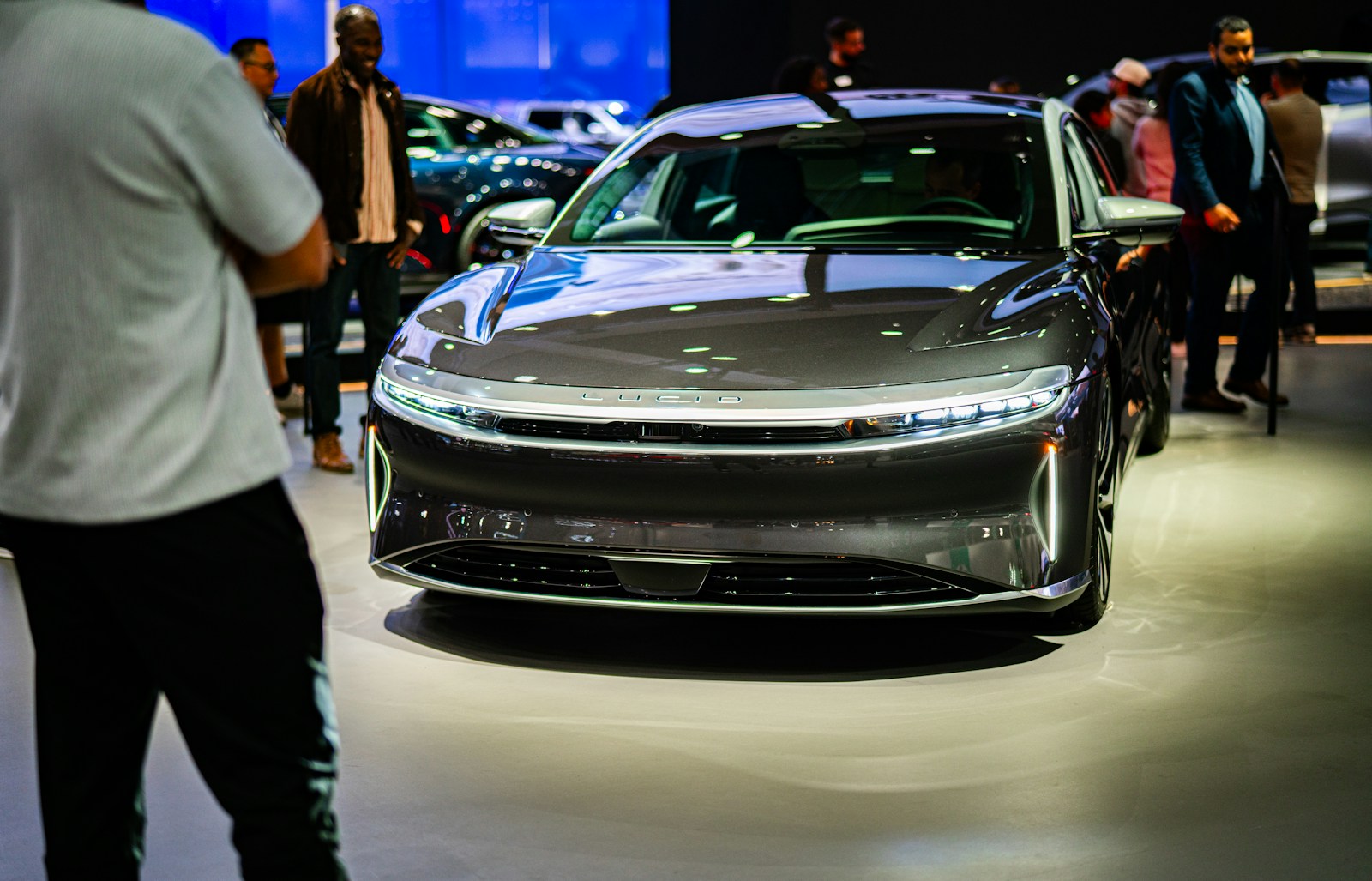 a group of people standing around a car on display