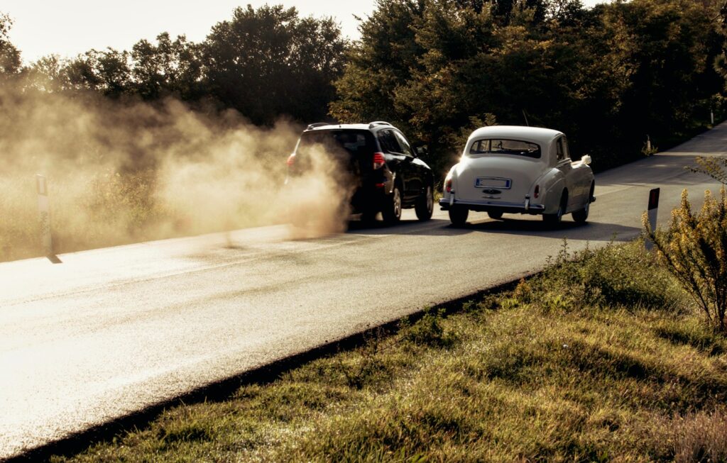 Two cars driving on a dusty road