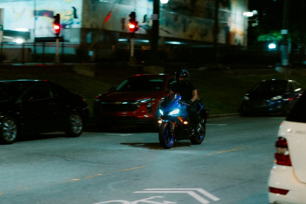 Motorcycle rides at night through a city street.