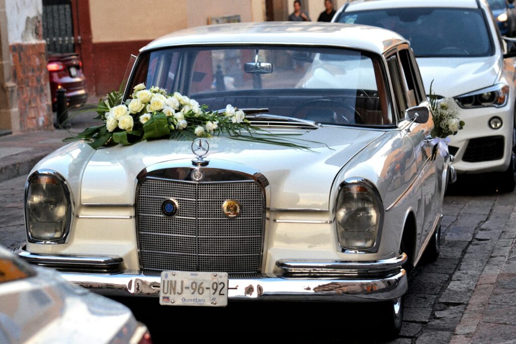 A vintage mercedes with wedding flowers is shown.