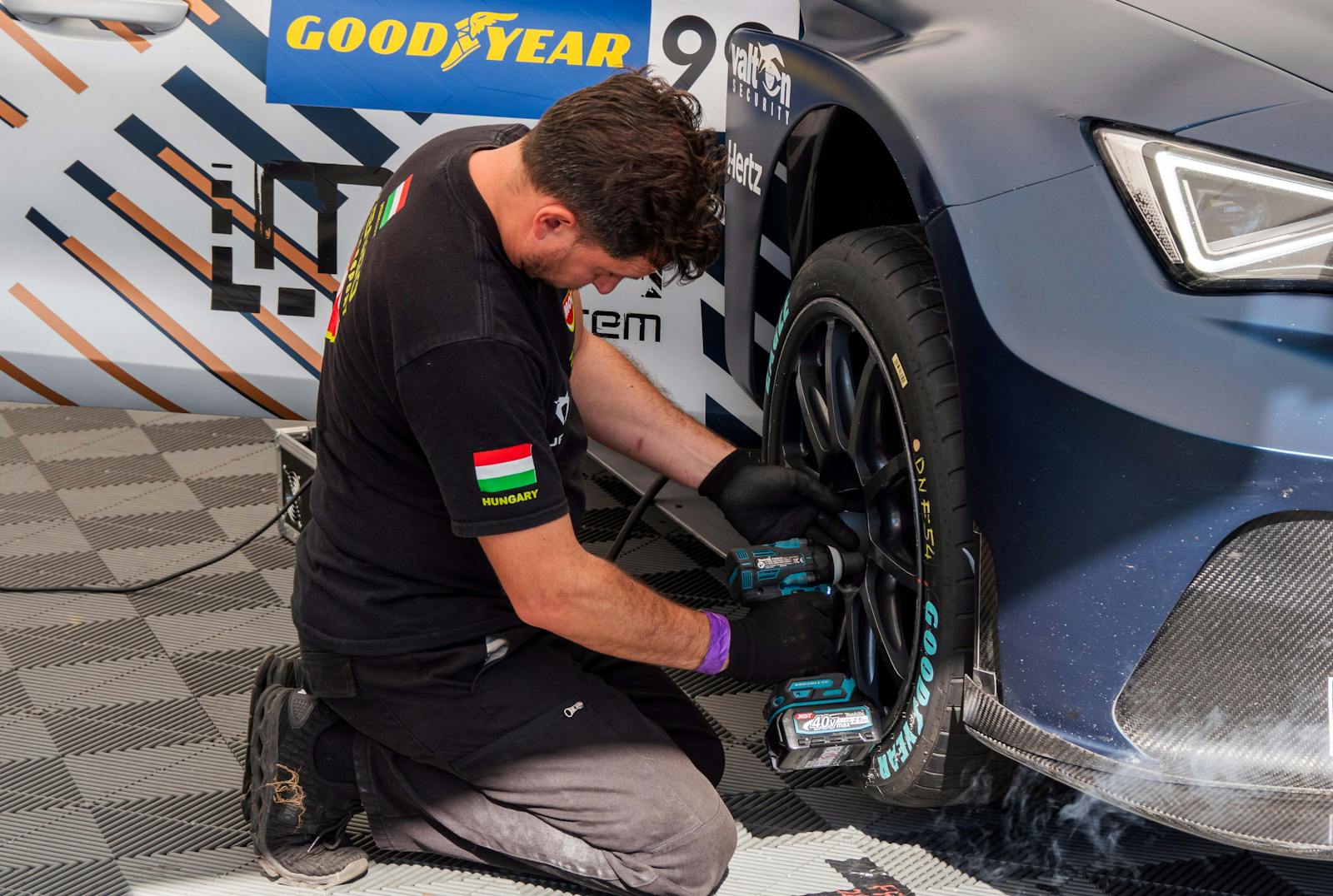 Mechanic fixing a car tire in a service station using power tools. Professional car maintenance.