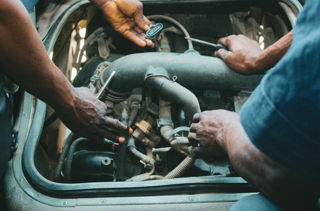 Mechanics working on a car engine in AK, Nigeria, showcasing teamwork.