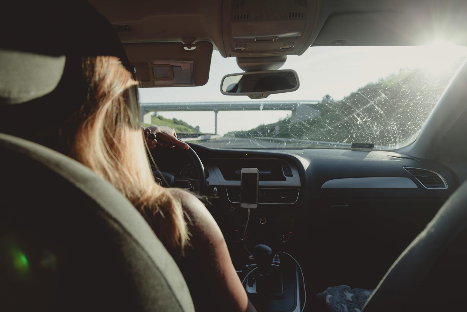 Woman driving on a highway during daytime, capturing road trip mood.