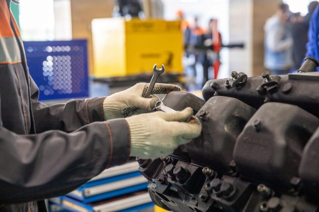 Close-up of a mechanic's hands working on an engine in a modern workshop.