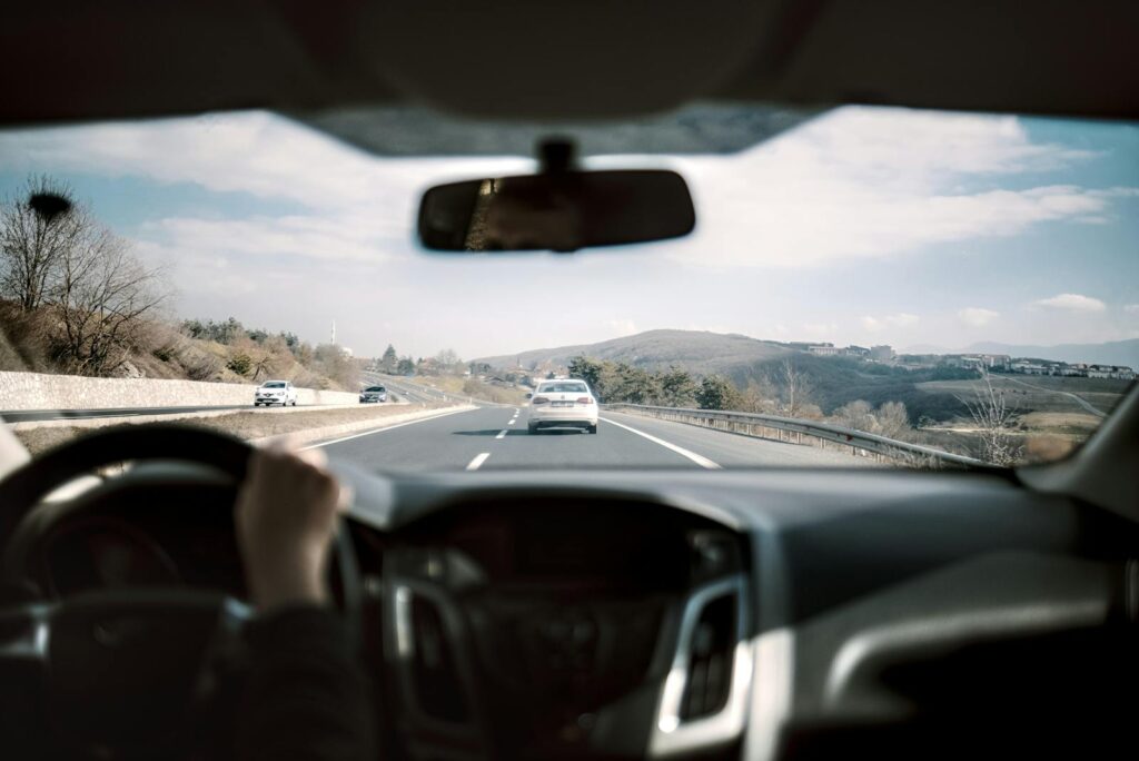 View from a car driving down a scenic highway with hills in the background, depicting a casual road trip.