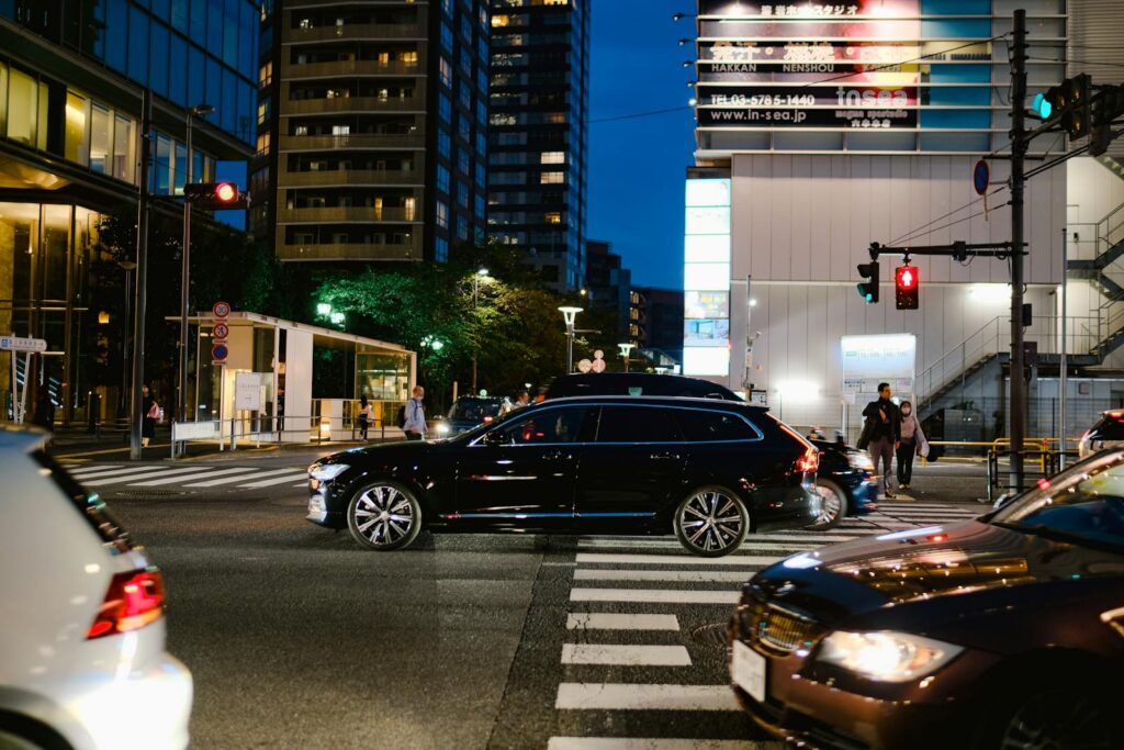 Dynamic city night scene with cars and pedestrians at a busy intersection under vibrant lights.