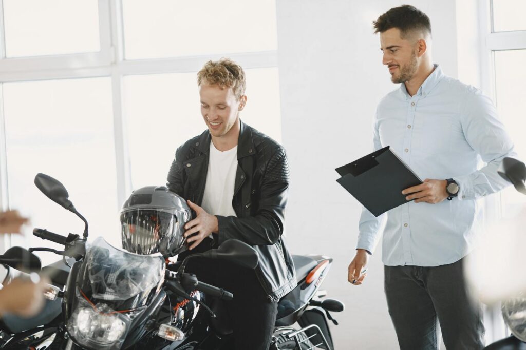 Two men at a motorcycle dealership discussing a motorbike purchase.