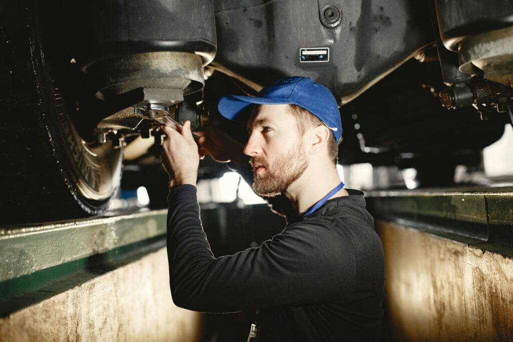 Auto mechanic working diligently on vehicle in workshop setting. Expertise in repair and maintenance.