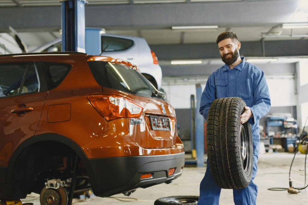 Mechanic holding a tire in a vehicle repair shop, showcasing automotive maintenance.