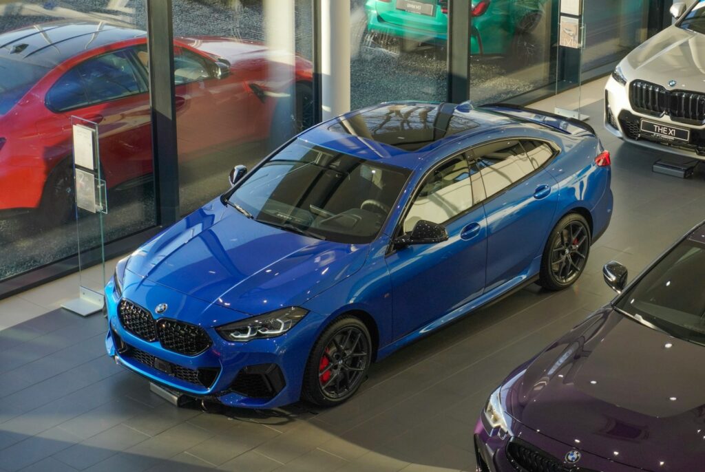 a blue car parked in a showroom next to other cars