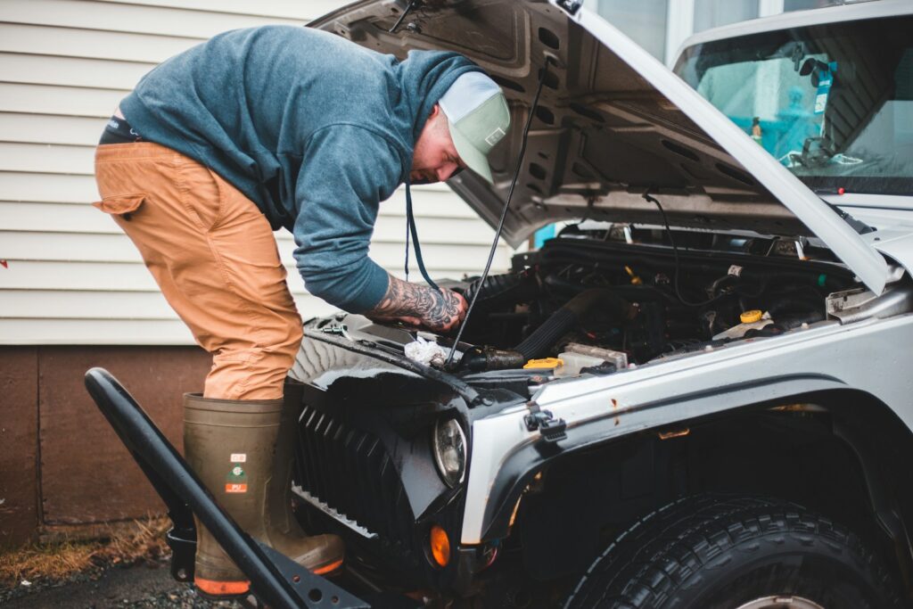man in blue long sleeve shirt and brown pants sitting on black car