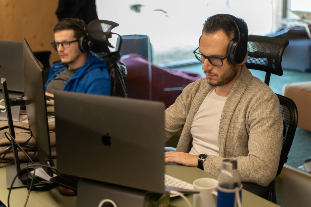 a man sitting in front of a laptop computer wearing headphones