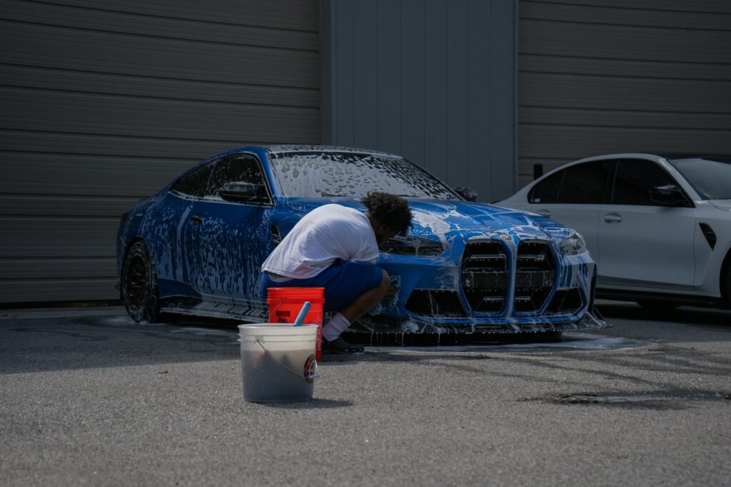 A person is washing a blue car with soap.