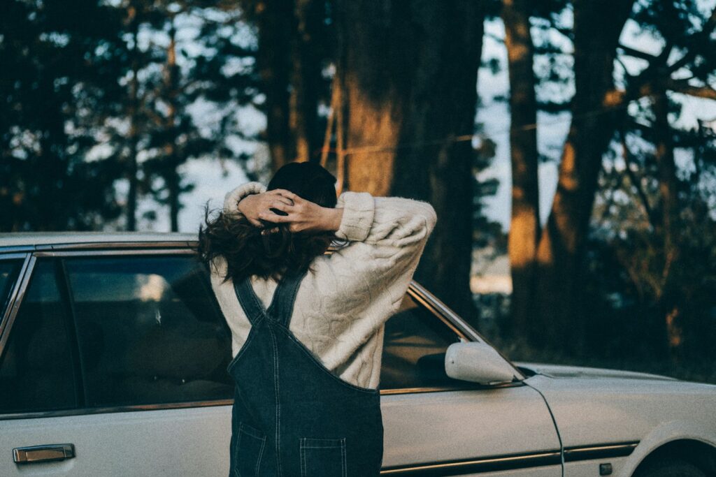 woman in gray long sleeve shirt standing in front of white car