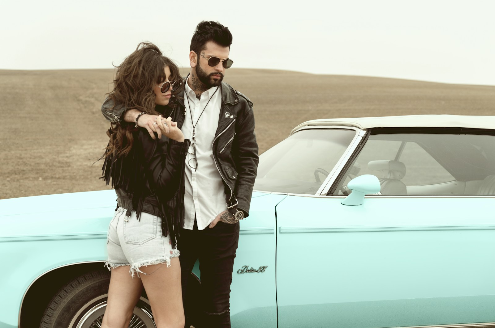 a man and a woman standing next to a car