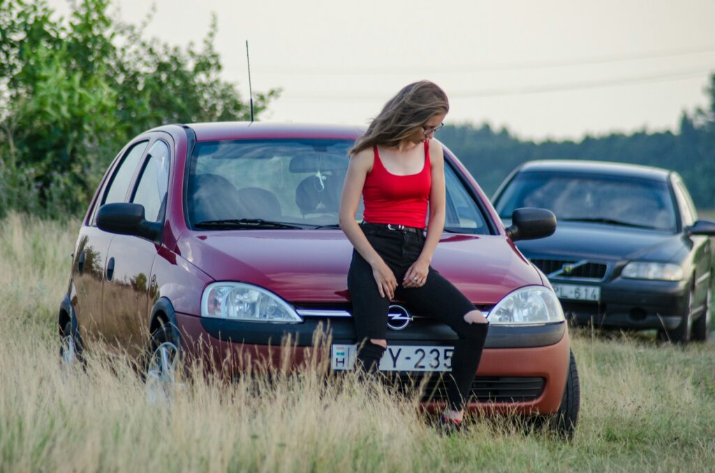 woman in black tank top standing beside red honda car during daytime