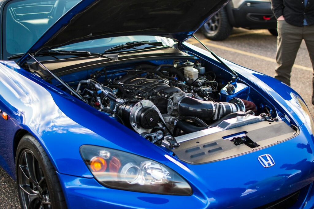 Blue sports car with its hood open, engine exposed.