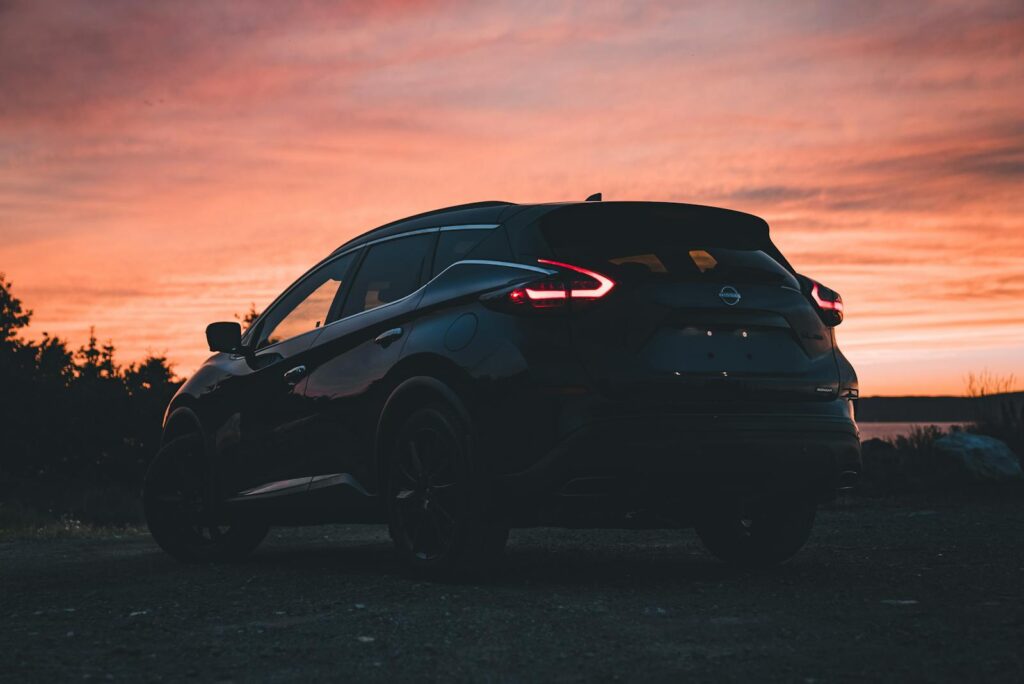 Silhouette of a Nissan Murano SUV captured at sunset, showcasing a vibrant orange sky.