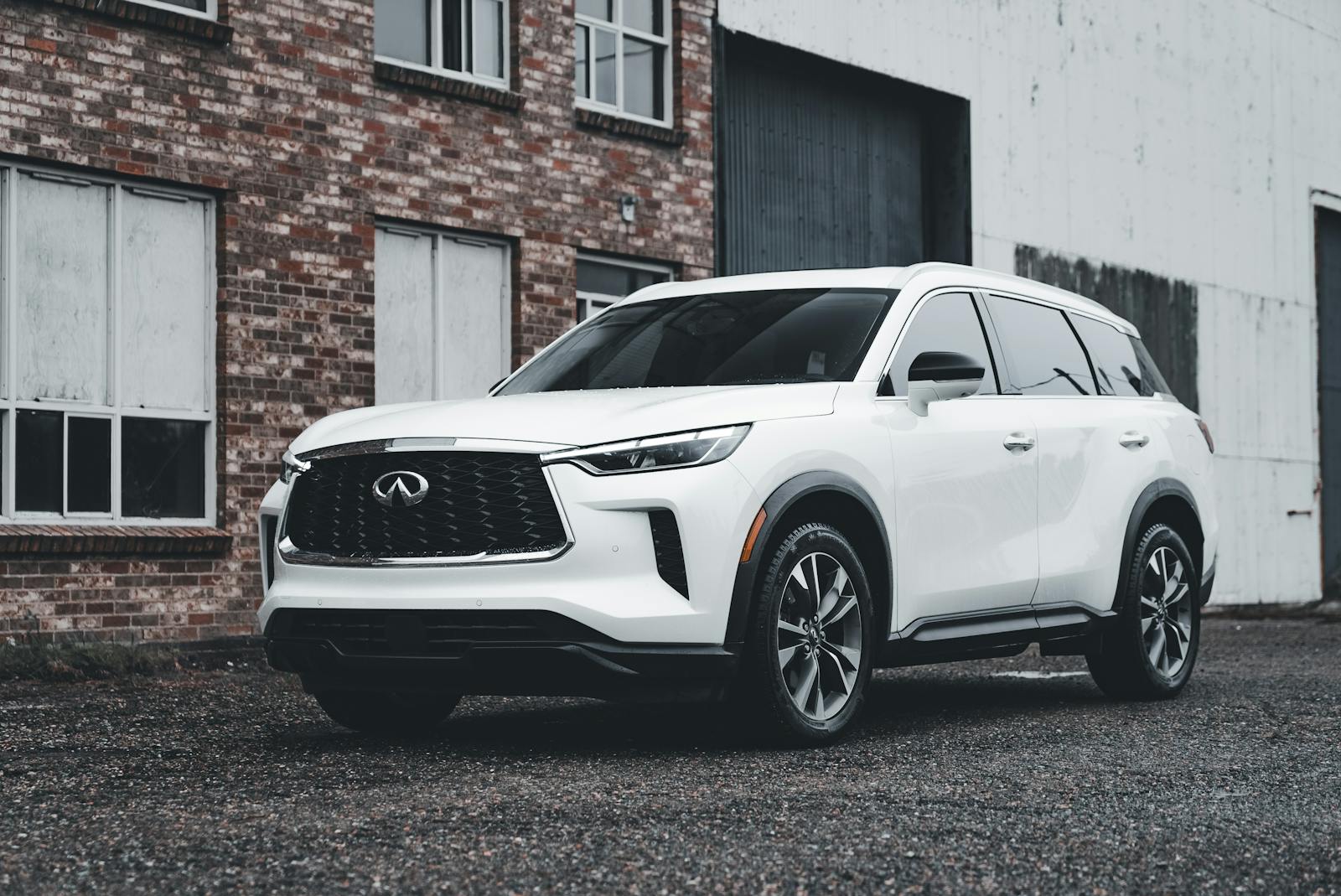 White luxury SUV parked outdoors in front of a brick building, showcasing modern automotive design.
