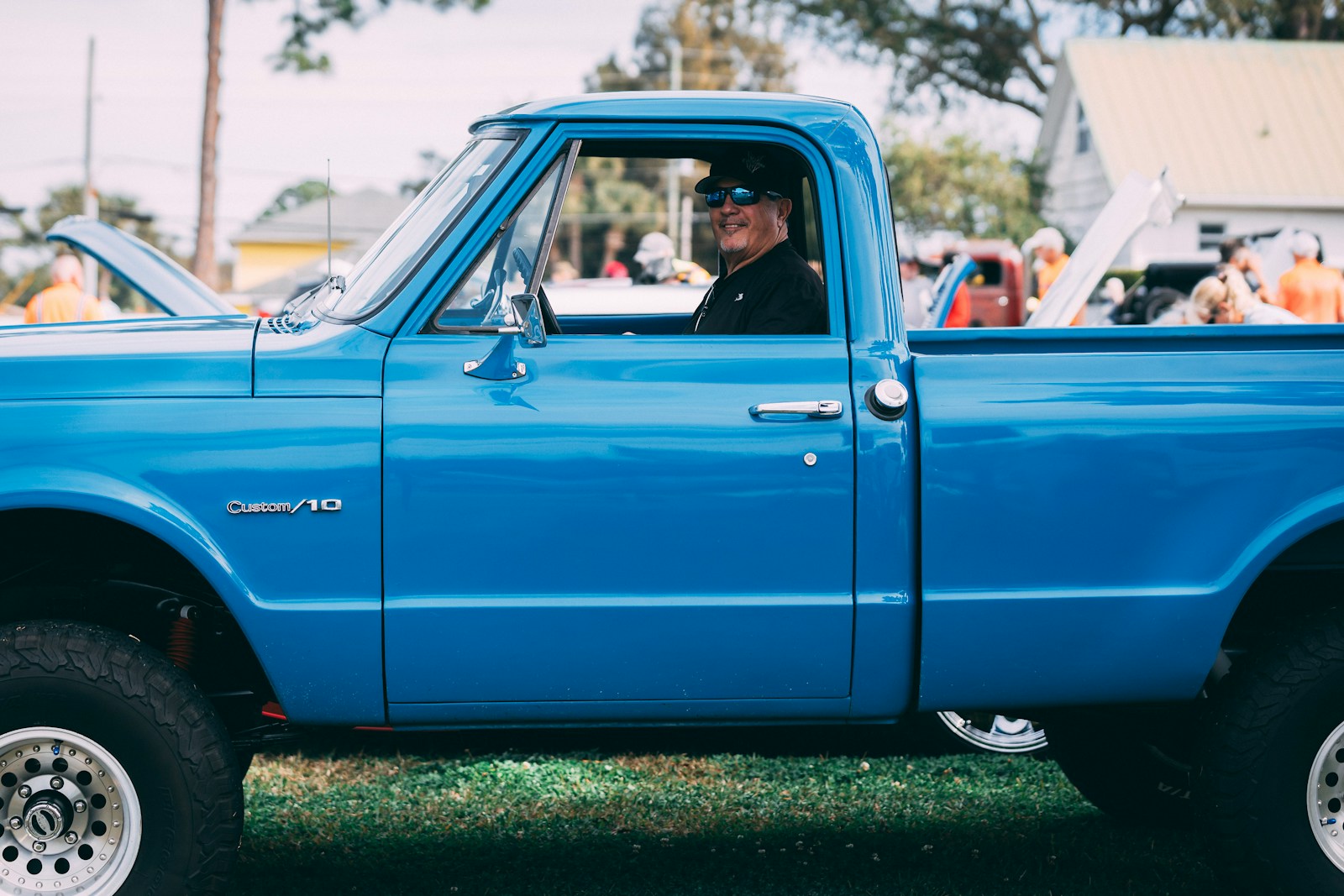 Man in sunglasses driving a bright blue pickup truck.